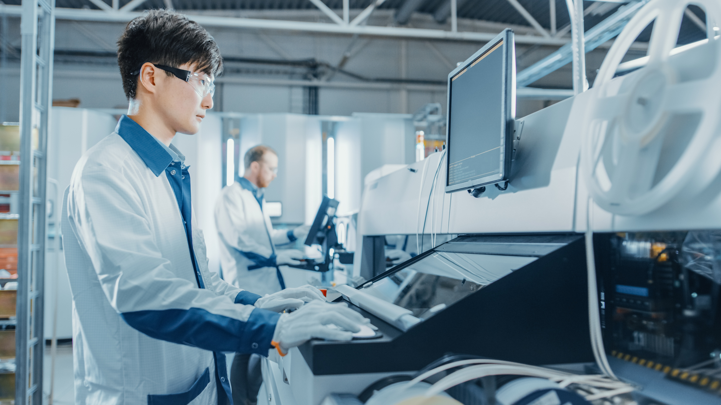 Electronic chip manufacturer wearing a lap coat, glasses, and gloves at work.