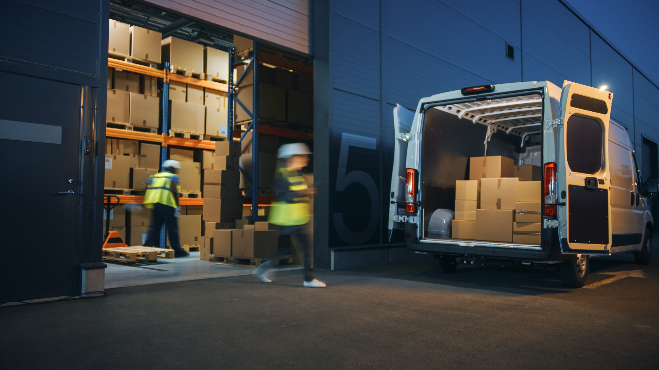 Boxes being taken from a warehouse and loaded into the back of a van.