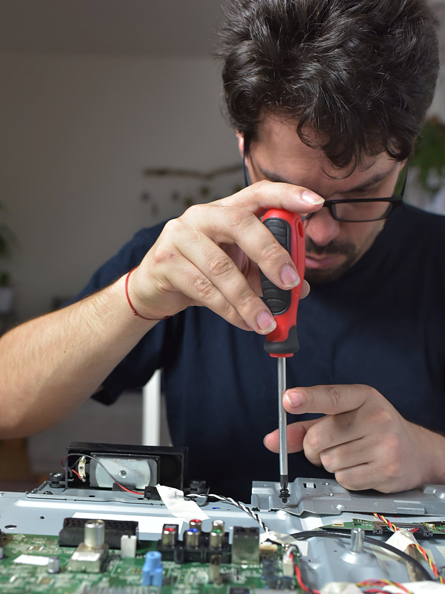 Man using a screw driver to repair an electronic device.