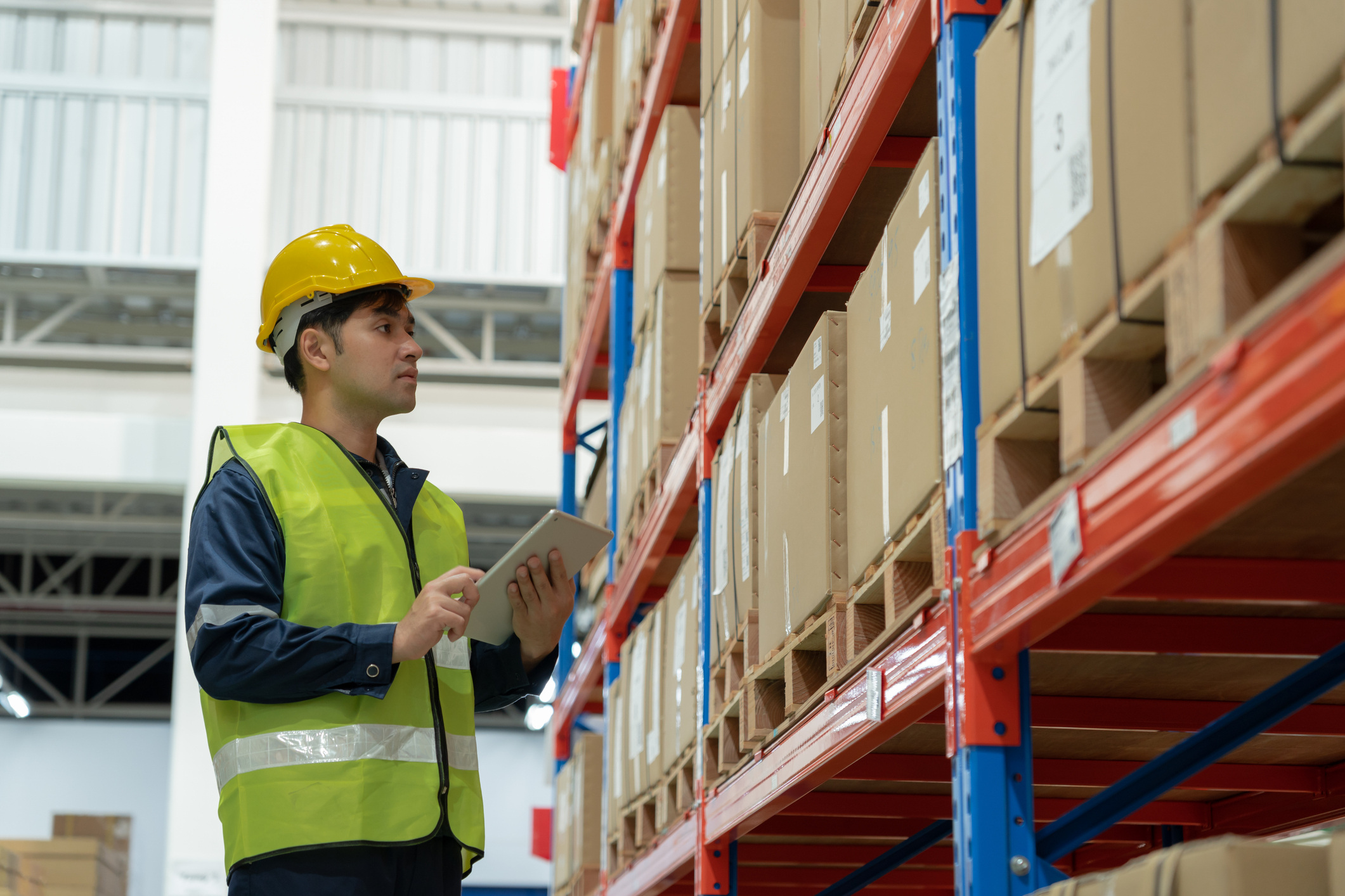 Person on a tablet checking boxes of stock in a warehouse.