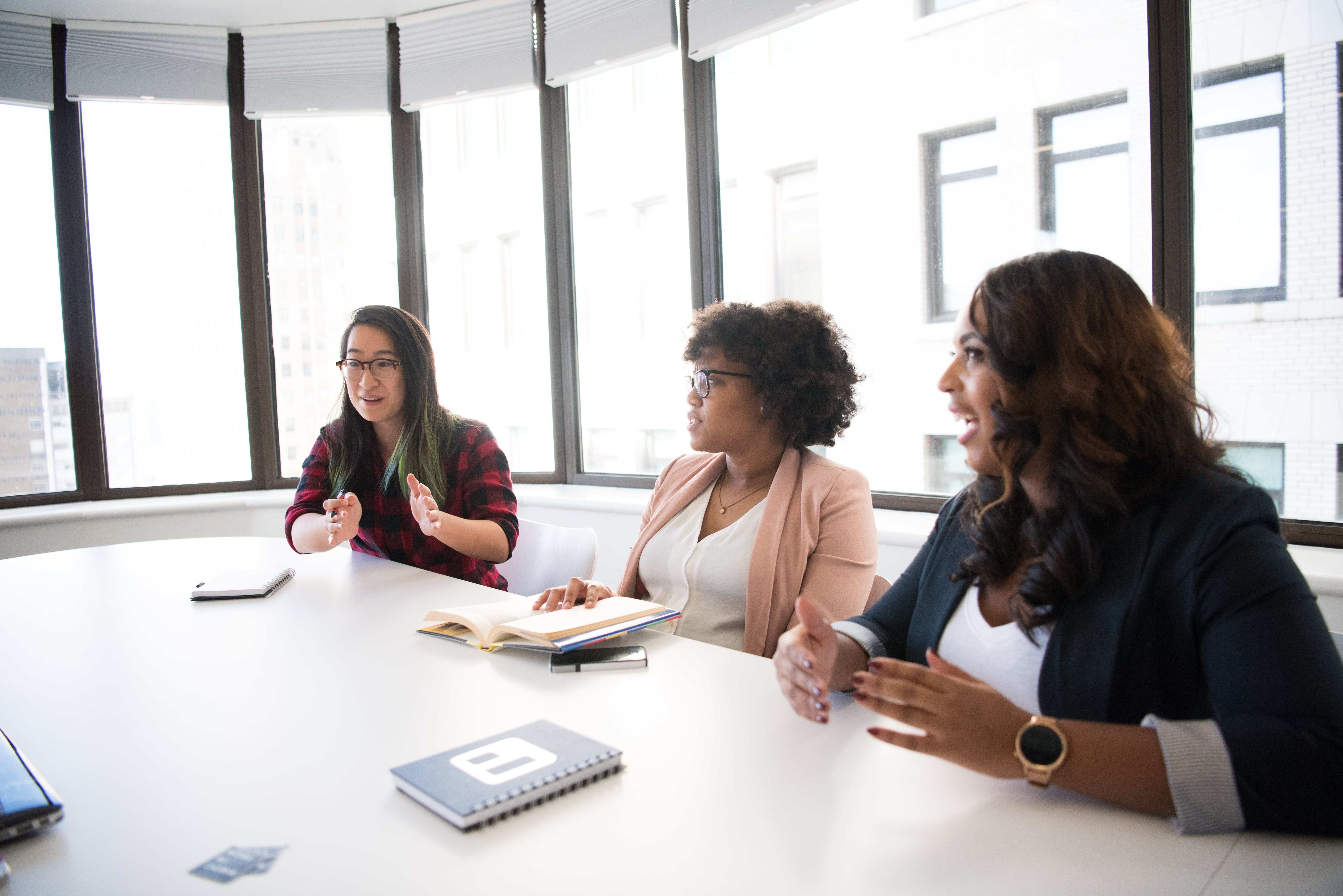 Women discussing at a boardroom table.