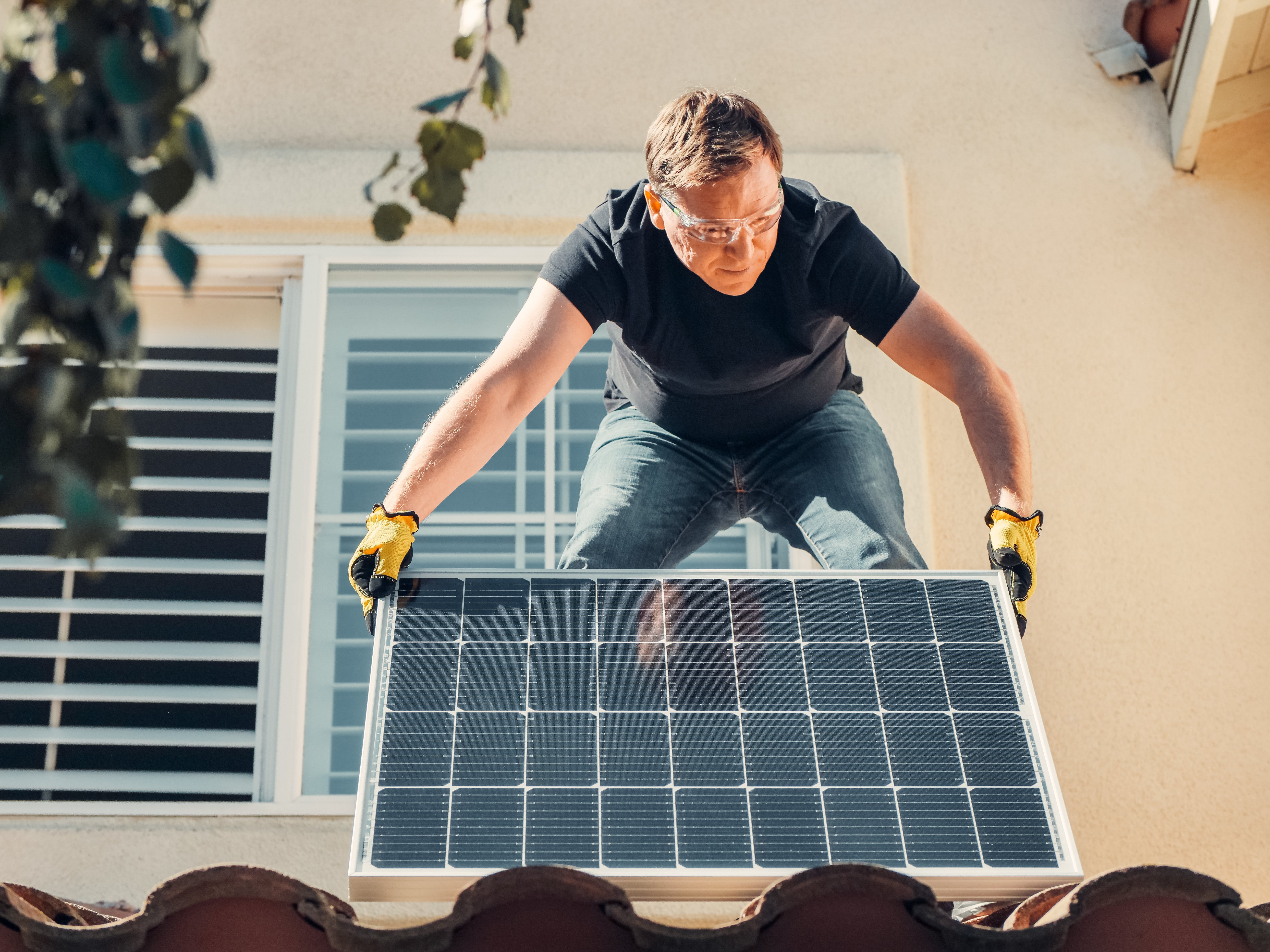 Man installing a solar panel on a roof.