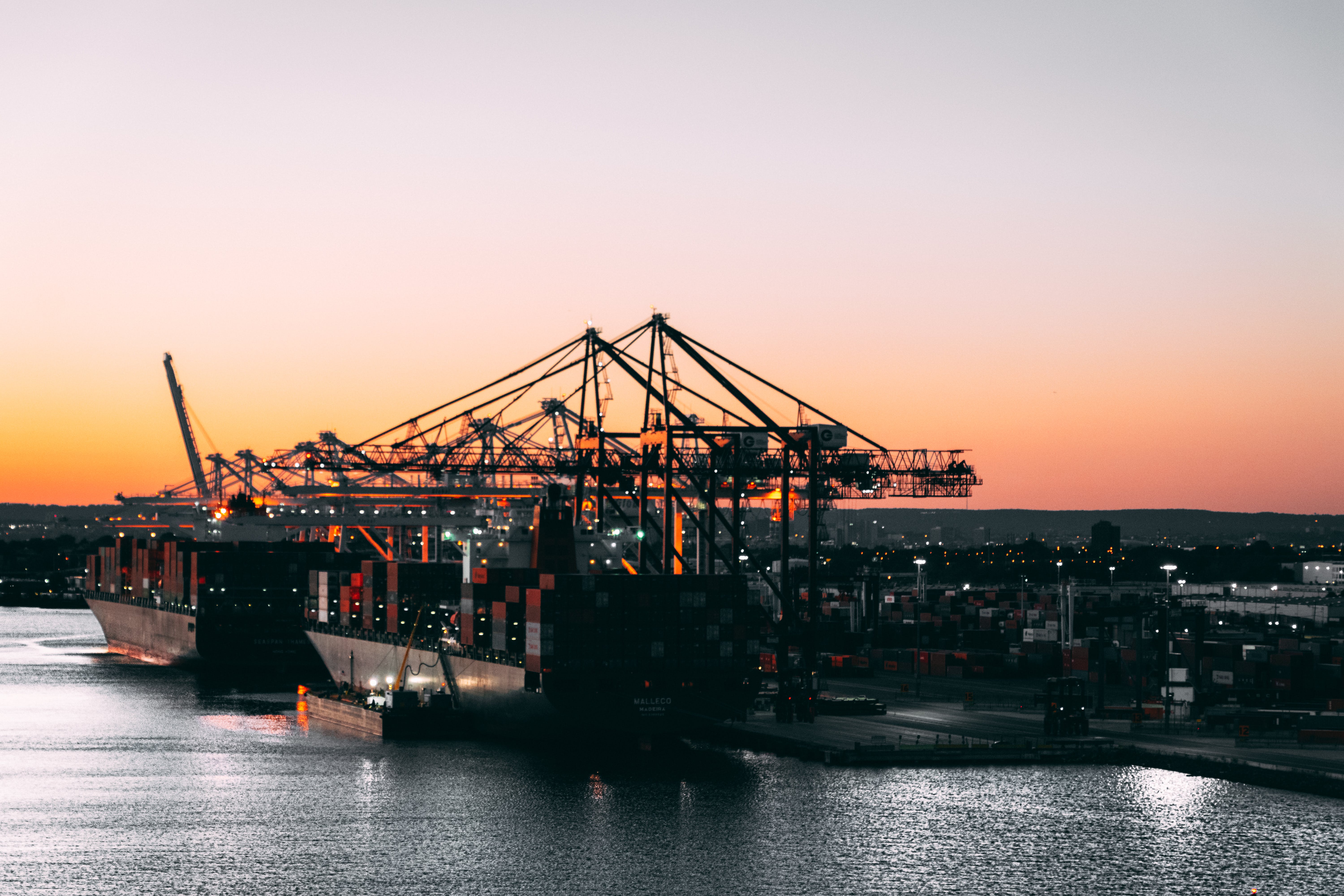 Ship loaded with shipping containers floating in a dock in the evening.